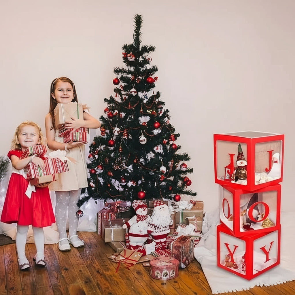 Two children holding presents in front of a decorated Christmas tree with a red and white decorative boxes.