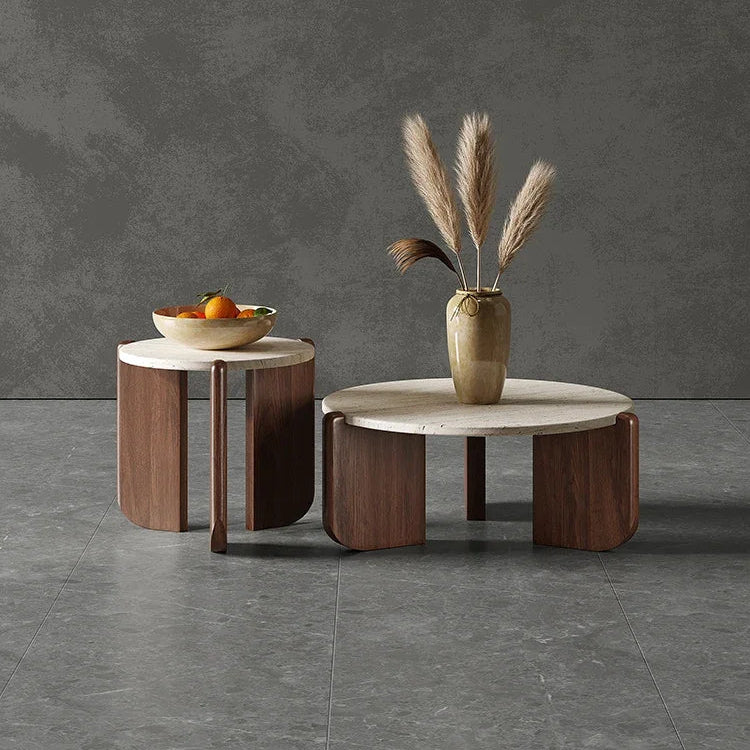 Two round tables with a vase of dried plants and a bowl of fruit on a dark gray background