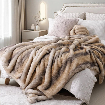 Beige and brown faux fur blanket draped over a bed in a bedroom setting.