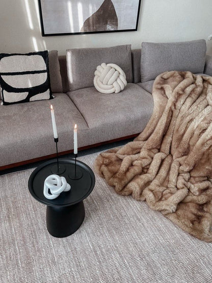 Living room with a gray sofa, decorative pillows, a beige throw blanket, and a small black table with candles.