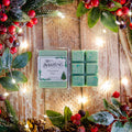 Green wax melts in a clear container with 'Sterling' branding, surrounded by Christmas decorations on a wooden background.